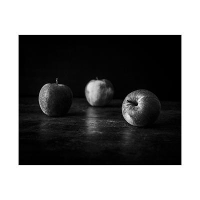 Trois pommes et des miettes sur la table de bois